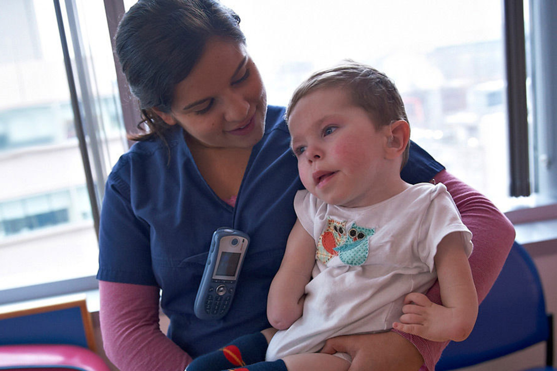 Nurse holding a child with limb differences.
