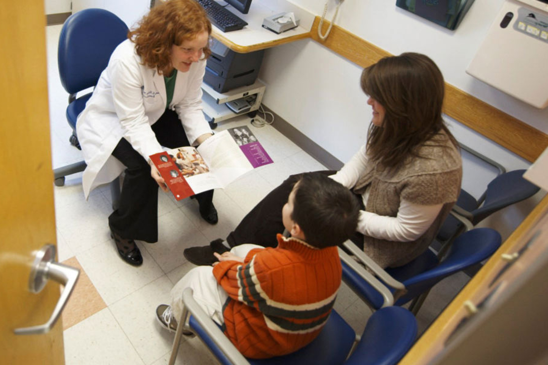 Doctor talks with mother and son in exam room.