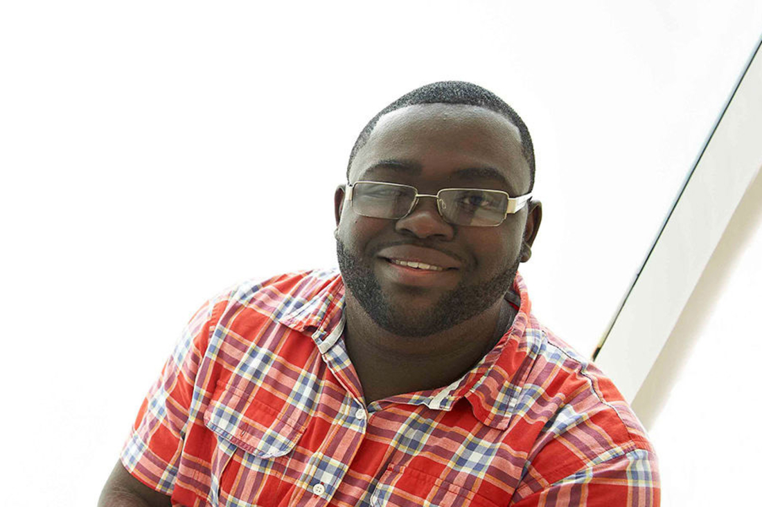 Man in red plaid shirt smiles at camera.