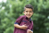 Smiling Hispanic boy wearing a purple shirt in the hospital garden