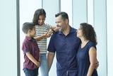 Older sister and parents smiling at their Hispanic son