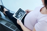 Mother-to-be glances at an ultrasound of her baby