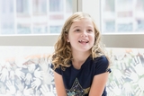 Blonde freckled girl sitting by the window and smiling