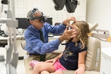 Blonde freckled girl getting her eyes examined by her ophthalmologist