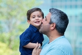 Dad kissing his smiling son in the hospital garden