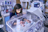 Baby in incubator receiving TLC from staff