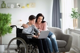 Son in wheelchair searching on the computer with mom