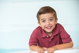 Smiling kid with green eyes and red polo shirt.