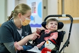 Nurse tickling smiling baby boy that has a feeding tube.