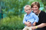 Boy sitting with mother in lush green courtyard.