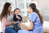 Mother and your child sitting in office talking to doctor.