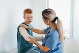 Doctor helping teen boy with broken arm.