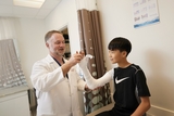 Boy with his doctor discussing a broken arm in a cast.