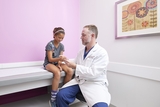 Girl with his doctor getting an assessment on her arm.