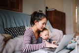 Mother looking at computer with baby on her lap