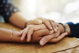 Comforting adult hands holding a teens hand