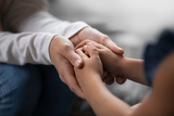Comforting adult hands cupping child hands