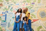 Family of four standing in front of a colorful mural