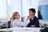 Teen having thyroid examined by physician