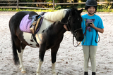 School aged girl standing next to a pony