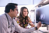 Two doctors analyzing a patient's scan on a hospital computer screen.
