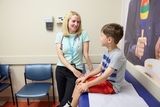 Doctor and patient talking and smiling at each other in an exam room.