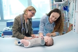 Two doctors examining baby patient in a hospital bed.