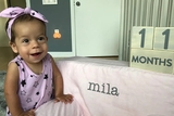 Smiling toddler in pink leaning on pink chair
