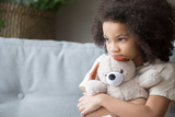 Scared young girl holding a stuffed animal Scared young girl holding a stuffed animal