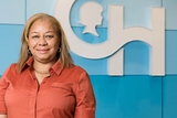 Woman in pink shirt with CH logo on blue wall