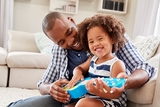 Father helping young daughter play ukulele Father helping young daughter play ukulele