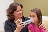 Mother helping daughter with inhaler Mother helping daughter with inhaler