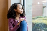 Adolescent girl sadly looking out window
