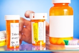 Hand reaching into medicine cabinet with pill bottles Hand reaching into medicine cabinet with pill bottles