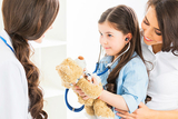 Young girl holding teddy bear and stethoscope