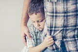 Young boy clinging to parent's leg Young boy clinging to parent's leg
