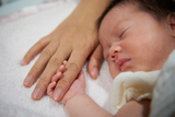 Infant holding onto finger Infant holding onto finger