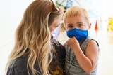 Mom holding son, both in masks Mom holding son, both in masks