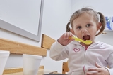 Young girl eating with a spoon Young girl eating with a spoon