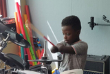 Child with amputated hands playing drums