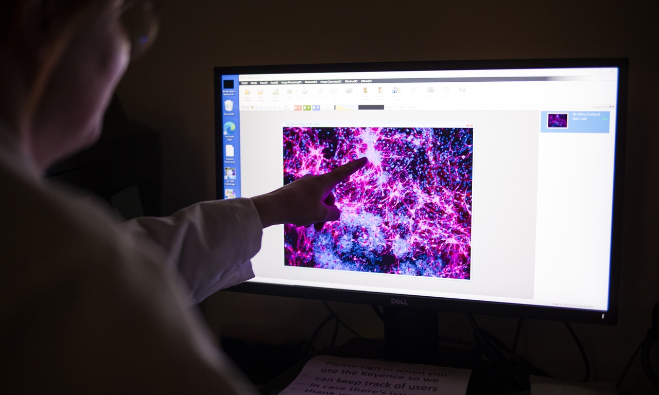 Person in dark room looking at a screen showing genetic material