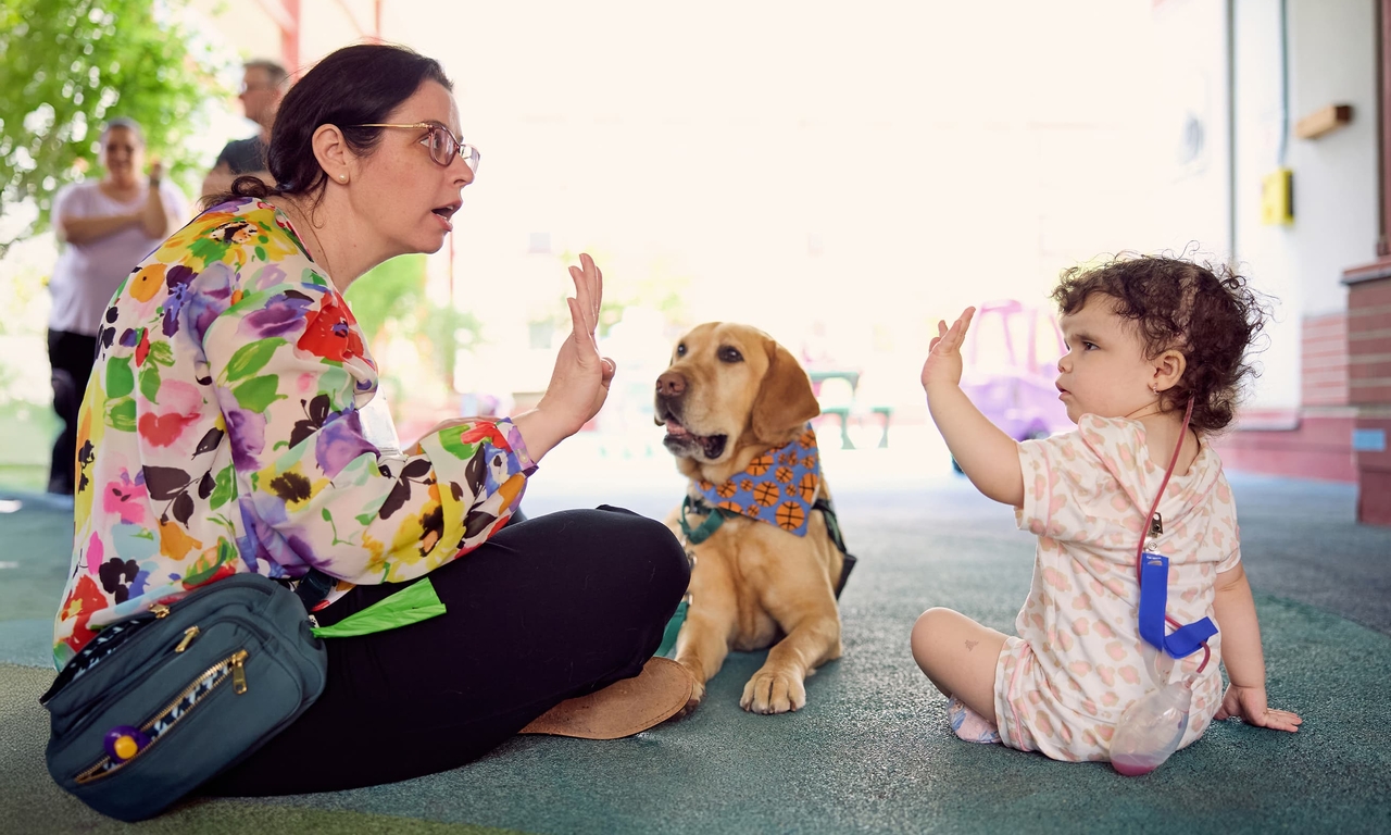 Lizzy teaches craniofacial patient Mya, 2, some hand signals to ask Dilly to do a trick.