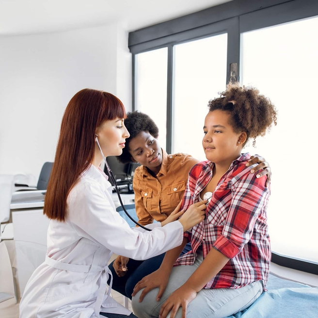 physican examining teen with stethoscope