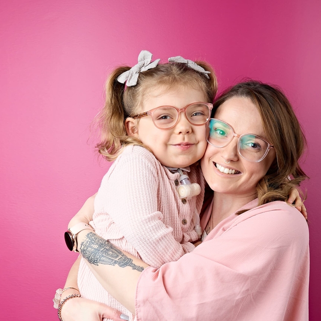 Mom hugging her blonde daughter with a tracheostomy
