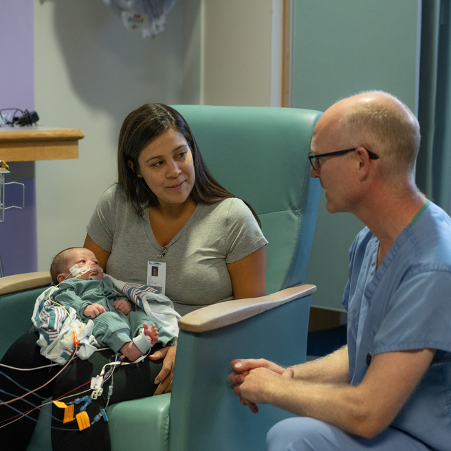 Mother holds her baby while chatting with staff