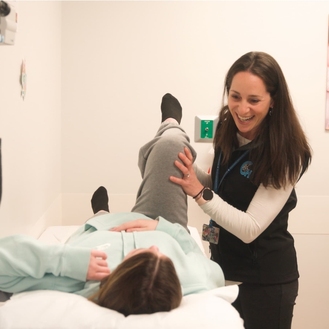 Female doctor helping teen girl with hip injury.