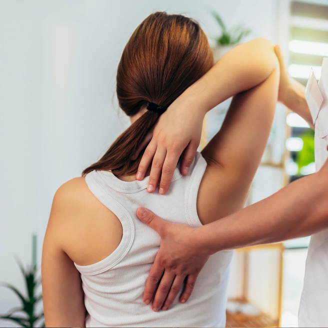 Teen girl in white tank top getting her spine checked out.