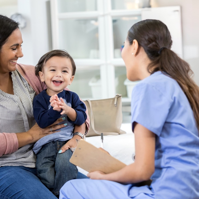 Mother and your child sitting in office talking to doctor.