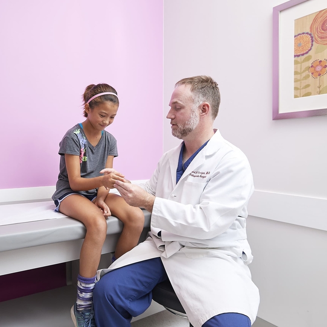 Girl with his doctor getting an assessment on her arm.