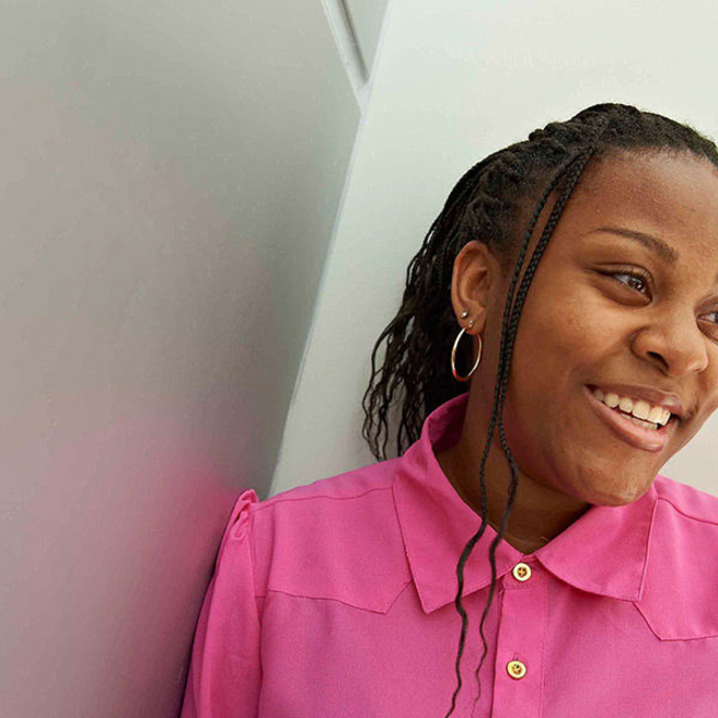 Teenage girl in bright pink shirt looking to the side and smiling.